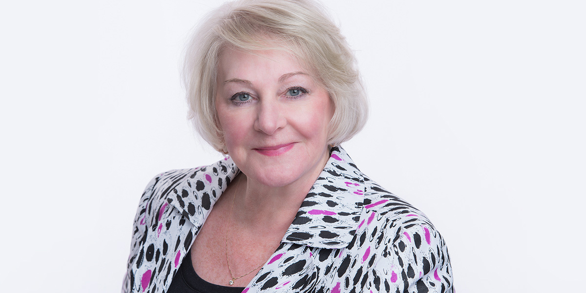 White haired mature woman smiles for the camera in Brian's studio for Annual Report Headshots in Niagara Region