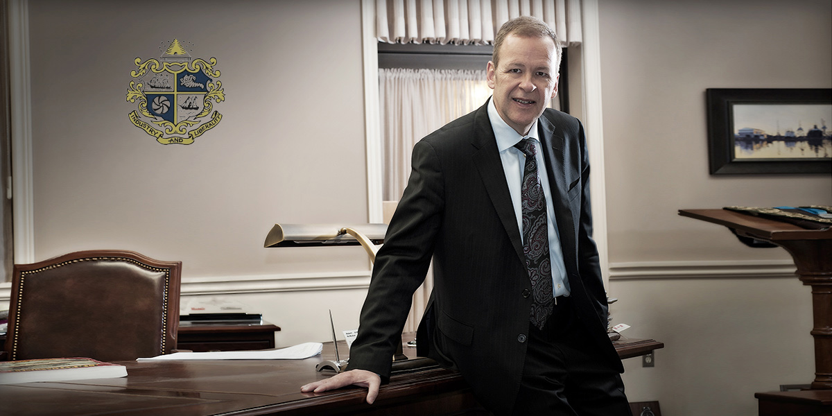 Mayor leans against his office desk for his publicity Headshots taken by Yungblut Photography at City Hall