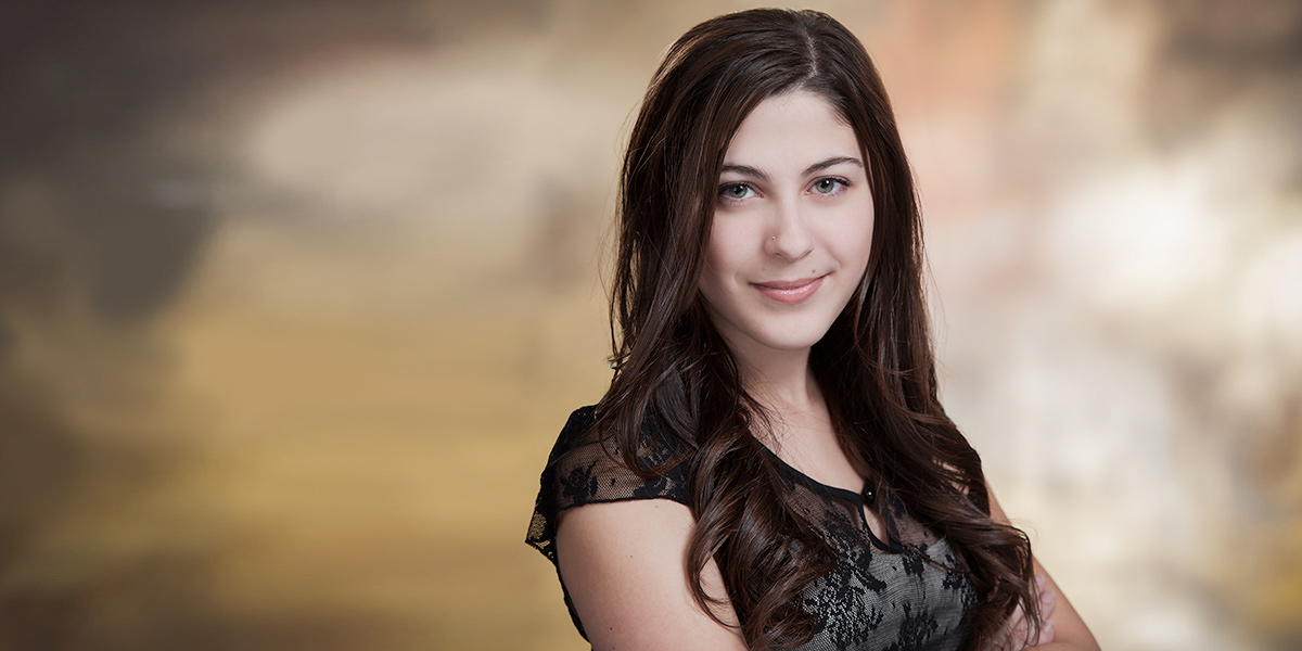 Young brunette woman's school headshot made in Thorold against a beautiful warm coloured studio backdrop by Yungblut Photographer 