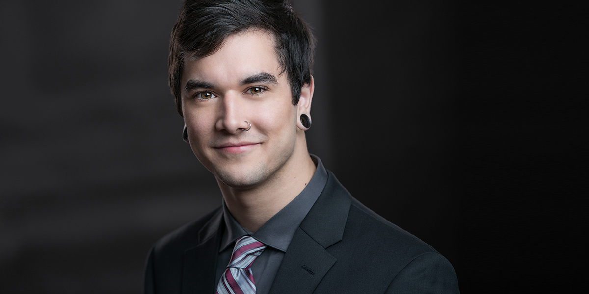 College Grad headshot made for school portfolio, he wears a dark suit with tie, low key portrait lighting by Yungblut