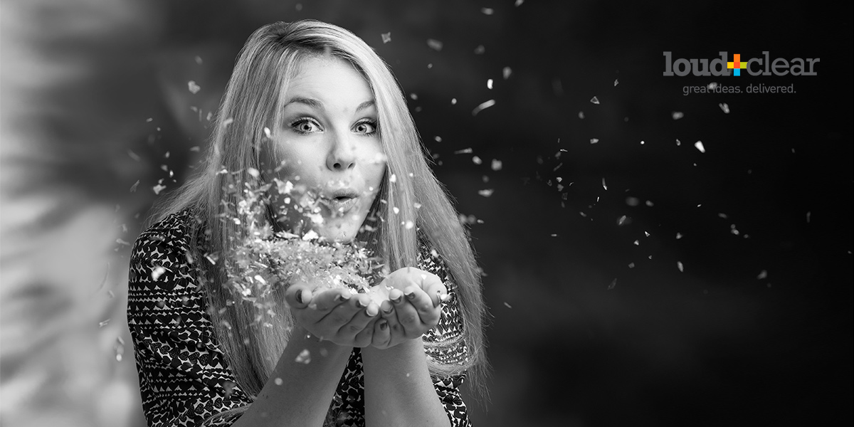 A woman blows sparkles from her hands as Brian Yungblut shoots her black and white Studio Headshots for Company Website